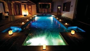 A swimming pool with a water feature at the center, surrounded by candlelit pathways and a building with a balcony. - Sankhara Private Beach Luxury Villas : Villa with Private Pool - Beach Front (Poste Lafayette)