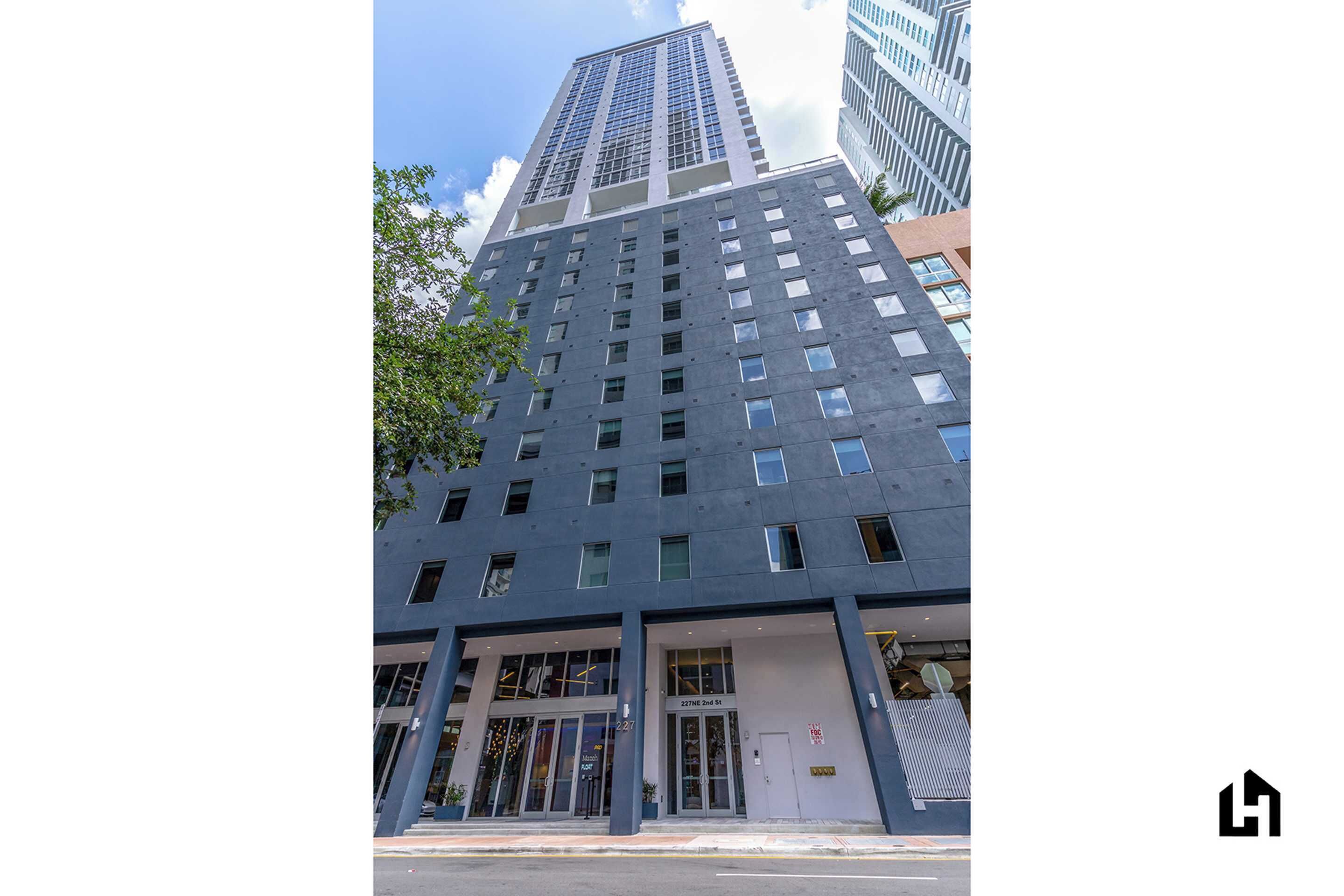 A modern high-rise building with a prominent entrance and a visible address sign.