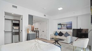 Una habitación de hotel moderna con una cama, un sofá, un televisor y un escritorio con una silla.