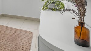 Un sofá beige con un tapete texturizado, una planta en maceta y una pared blanca.