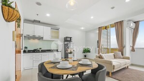 Un salón moderno con sofá, mesa de comedor y cocina al fondo.