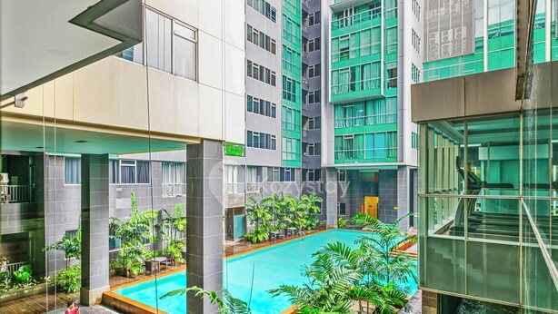Un área de piscina interior moderna con vistas despejadas a edificios circundantes y una terraza de madera.