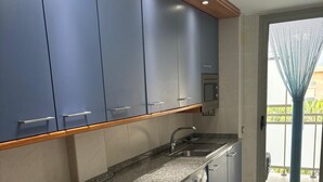Una cocina moderna con armarios grises, lavadora integrada y encimera de granito.