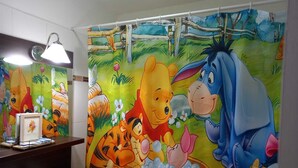 Une salle de bain décorée d’une fresque représentant Winnie l’ourson et Tigrou, avec un lavabo et un miroir.