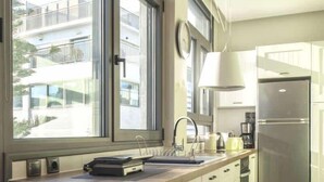 A modern kitchen with a large window, a stainless steel refrigerator, and a white countertop. - Luxury Haven in the most ideal area of Athens (Athina)