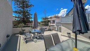 An outdoor patio with a table and chairs, a covered umbrella, and a glass table. - Luxury Haven in the most ideal area of Athens (Athina)