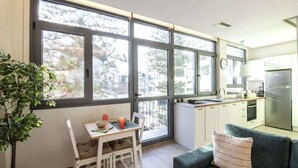A modern kitchen with large windows, a dining area with a table and chairs, and a sofa. - Luxury Haven in the most ideal area of Athens (Athina)