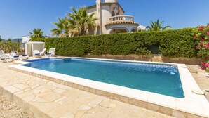 Ein Swimmingpool mit Liegestühlen und ein Gebäude mit einem Balkon im Hintergrund.