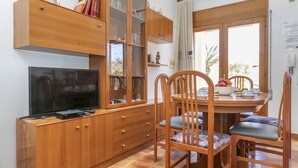 Eine kompakte Küche mit integriertem Fernseher, Holzschränken und einem Essbereich mit Stühlen und Tisch.