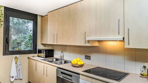 A modern kitchen with light wood cabinets, a black microwave, a sink, a dishwasher, and a stove.