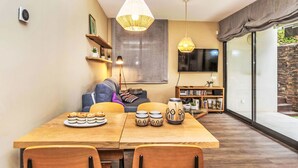 A dining area with a wooden table, chairs, and a TV in the background.