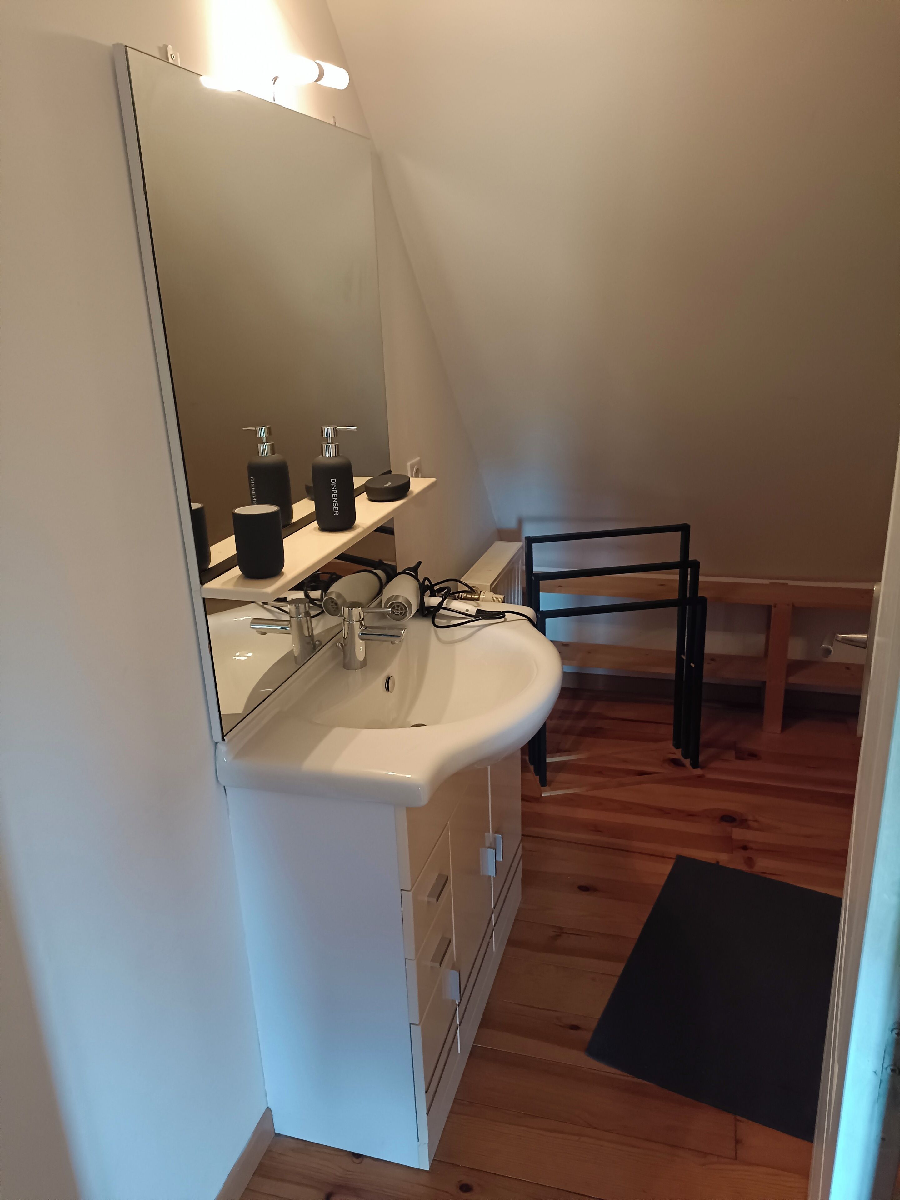 A bathroom with a white sink, mirror, and black toiletries.