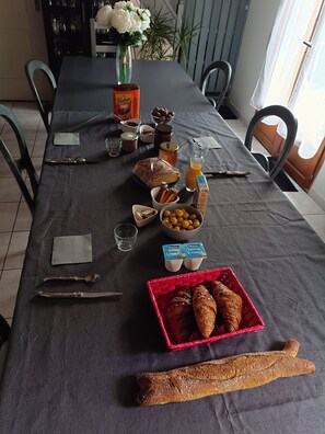 A dining table set with various food items, utensils, and a vase of flowers.