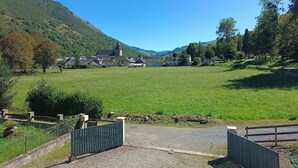 A rural landscape with a church, open fields, and a mountain backdrop. - Chambre et Table d'Hôtes (Campan)
