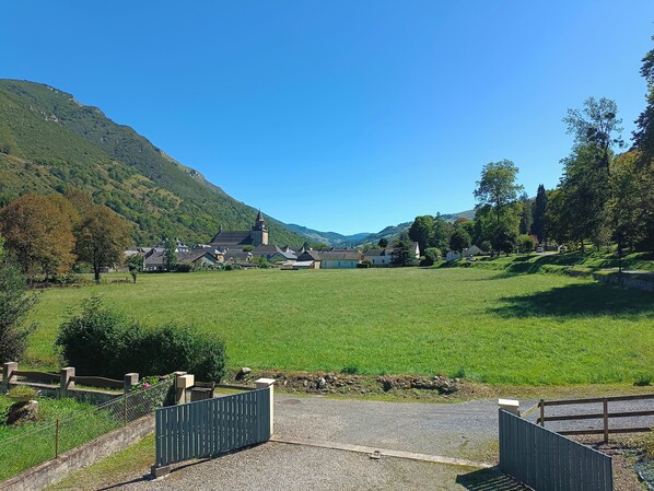 A rural landscape with a church, open fields, and a mountain backdrop.