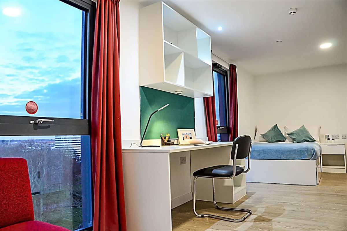 A modern bedroom with a desk, chair, and bed.
