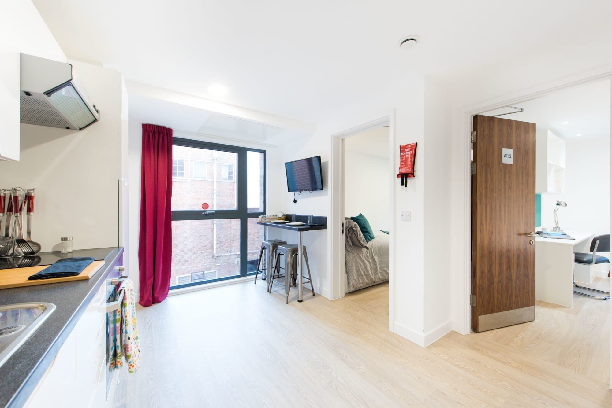 A modern kitchen with a window, a dining area with a table and chairs, and a wooden door.