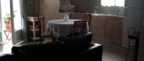 A kitchen with a dining table, chairs, cabinets, and a refrigerator.