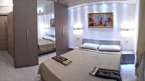 Une chambre d’hôtel moderne équipée d’un grand lit, d’une armoire, d’un bureau avec une chaise et d’une petite table.