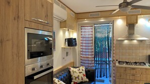 A modern kitchen with a gas stove, oven, and microwave. There is a black leather sofa with patterned cushions and a ceiling fan. - Apartment close to the Scala Dei Turchi Beach (Realmonte)