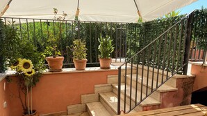 A covered outdoor area with a wooden bench, a metal staircase, and potted plants. - Apartment close to the Scala Dei Turchi Beach (Realmonte)