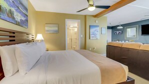 A hotel room with a bed, a seating area, a ceiling fan, and artwork on the walls. - Beach & Tennis 1802 (Bonita Springs)