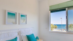 Un dormitorio con una cama, almohadas blancas y vistas al mar.