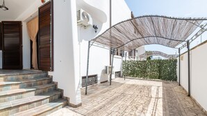 Un espacio al aire libre cubierto con suelo de piedra, una escalera que conduce a una puerta y un equipo de aire acondicionado fijado a la pared.
