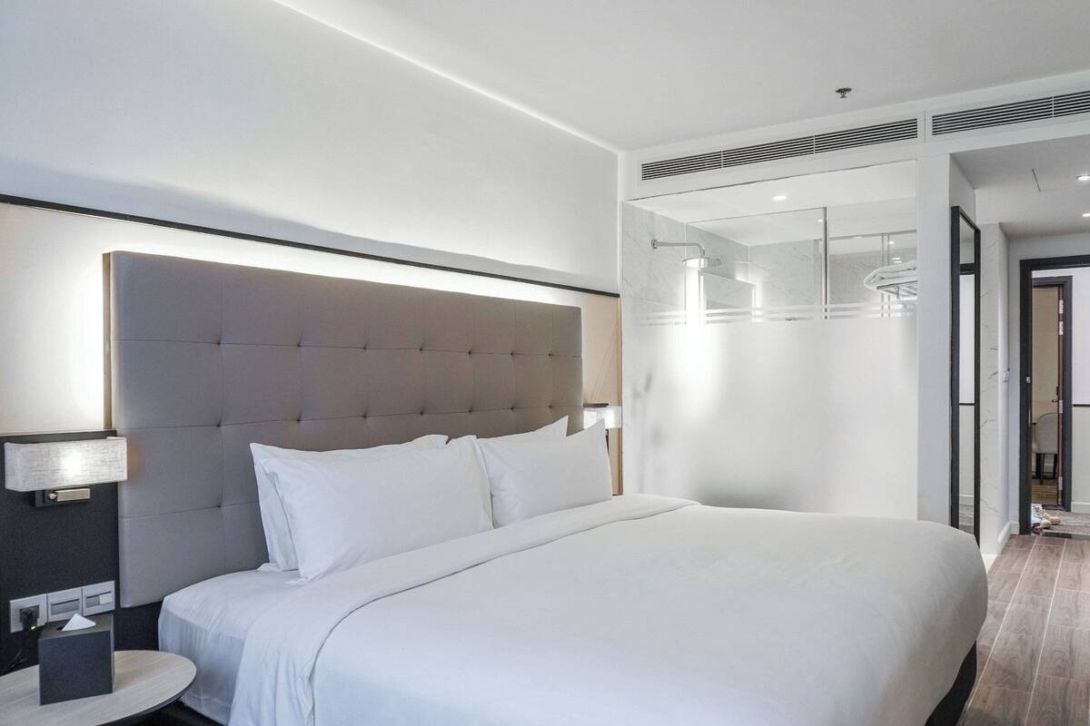 Une chambre d’hôtel moderne avec un grand lit, une table de chevet et une petite table d’appoint.