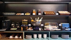 Montaje de bufé con diversos alimentos, salsas y una estación de café.