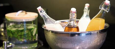 A metal bowl containing several bottles with liquids, a glass jar with a lid, and a metal container with a lid.