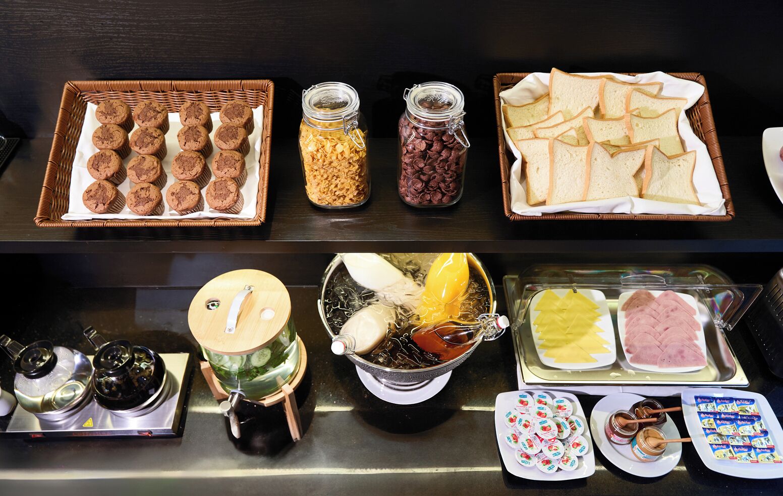 Een buffet met diverse etenswaren, zoals koekjes, granola, brood en verschillende soorten spreads en dips.