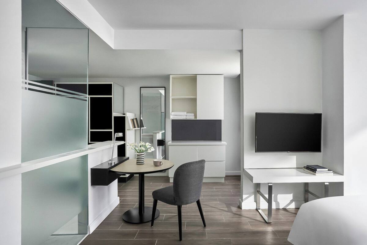 Une chambre d’hôtel moderne équipée d’un lit, d’un bureau, d’une chaise, d’une télévision et d’une armoire.