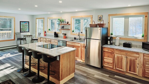 Une cuisine moderne avec des meubles en bois, un réfrigérateur en acier inoxydable et un coin bar équipé de tabourets.