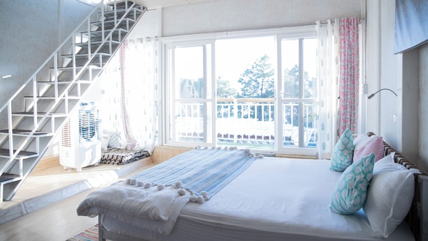 Un dormitorio con una cama grande, una escalera y vistas al exterior.