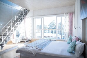 A bedroom with a large bed, a staircase, and a view of the outside. - Acanti Dharamshala (Dharamshala)