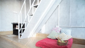 Una habitación moderna con una cama roja, paredes blancas y suelo de madera.
