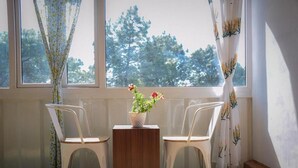 Una habitación con dos sillas blancas, una pequeña mesa de madera y una planta en maceta con flores.