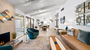 Un salon moderne avec une cheminée, un canapé, un coin repas et une cuisine en arrière-plan.