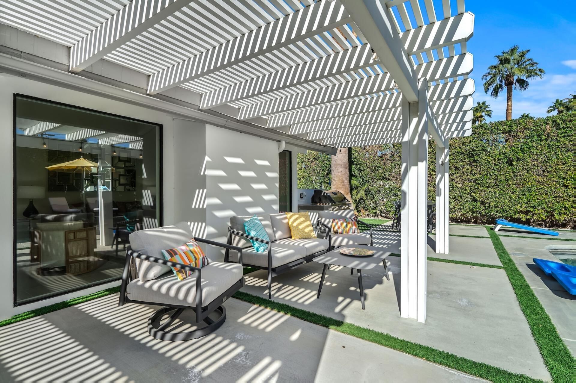 A covered outdoor seating area with modern furniture and a grill.