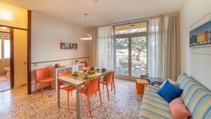 Ein Essbereich mit Tisch und Stühlen, einer Couch und einem Fenster mit Vorhängen.
