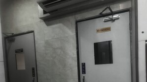 A hallway with two doors, one marked 'PUSH' and the other 'PULL'. There is a 'NO SMOKING' sign above the 'PULL' door. An air conditioning unit is mounted above the hallway. - Green Apple PG & Dormitory (Mumbai)