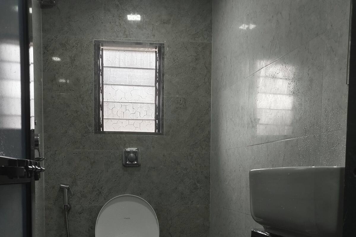 A small bathroom with a toilet, a window, and a sink.