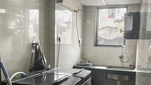 A compact kitchen with a tiled floor, a sink, a window, and a water dispenser. - Green Apple PG & Dormitory (Mumbai)