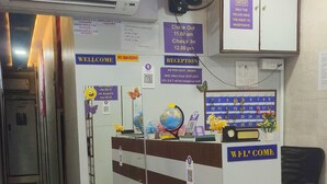 A reception area with a desk, a clock, a globe, and a notice about police investigation rights. - Green Apple PG & Dormitory (Mumbai)