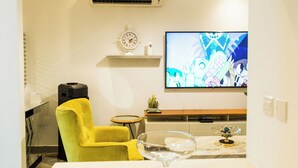 Eine moderne Küche mit einem gelben Stuhl, einem an der Wand befestigten Fernseher und einer Marmorarbeitsplatte.