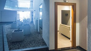 Ein modernes Interieur mit Fliesenboden, einem kleinen Innenhof und einer Tür zu einem weiteren Raum.