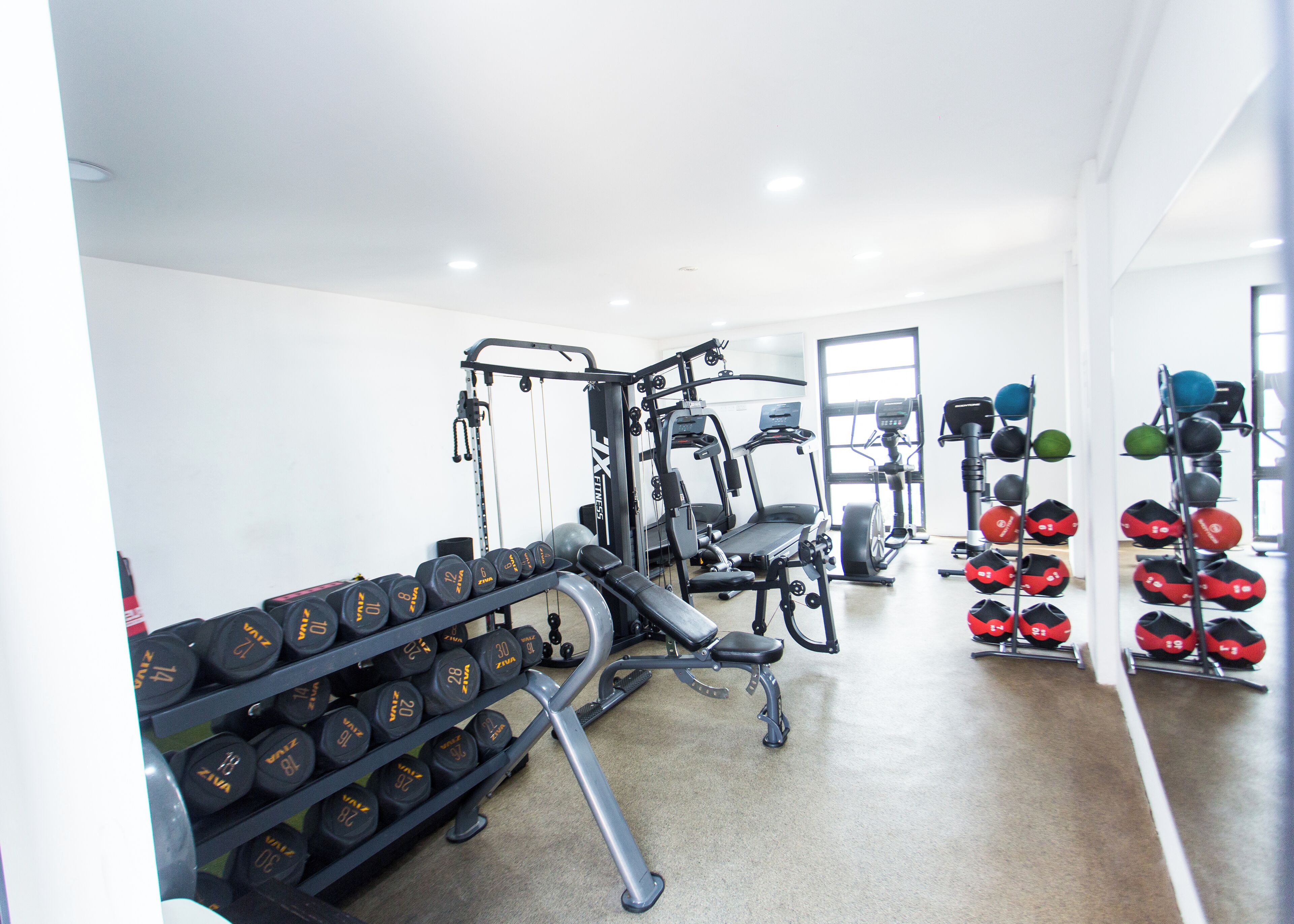 A gym with various exercise equipment, including dumbbells, a treadmill, and weight machines.