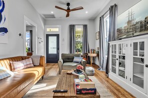 Uma sala de estar com sofá, poltrona, mesa de centro e um aparador com portas de vidro.
