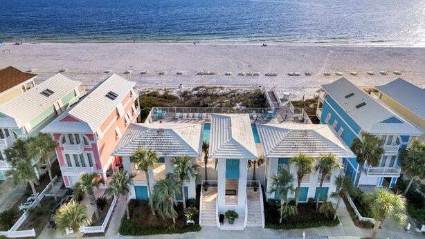 Ein Strandhotel mit mehreren bunten Gebäuden, einem Poolbereich und Palmen.